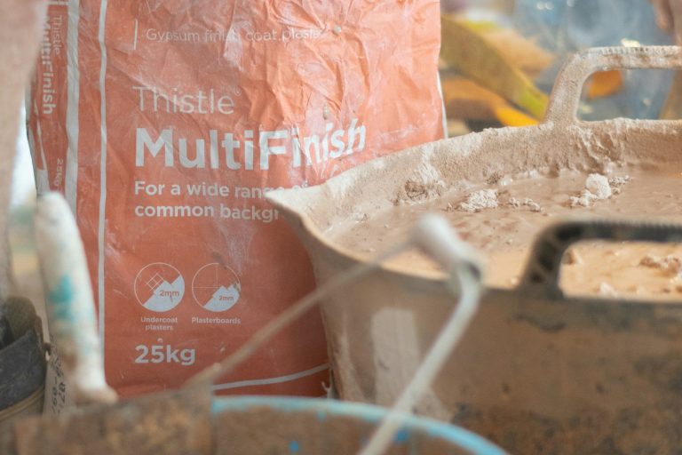 Bag of MultiFinish plaster with mixing tools and a container in the background.
