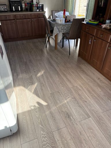Wooden flooring in a kitchen with a table and chairs in the background.