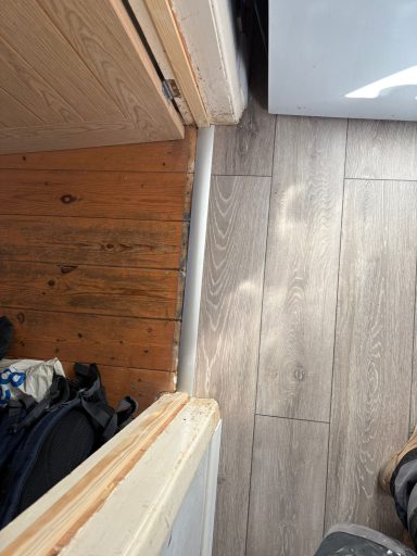 Wooden floor meets a light-coloured laminate surface in a doorway.