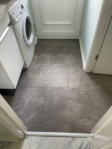 Grey tiled floor with a washing machine visible in a small room.