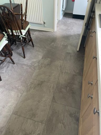 Light grey flooring with wooden cabinets and a dining area in the background.