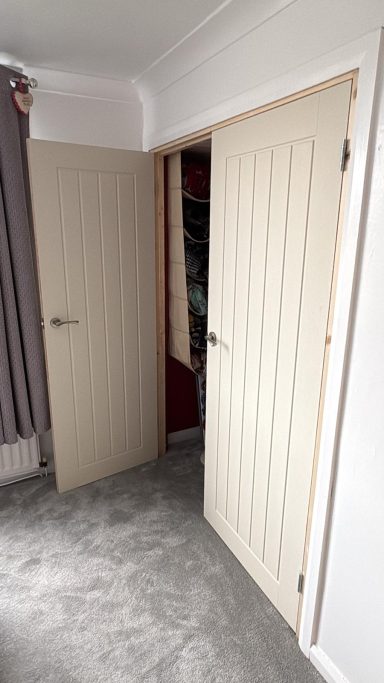Interior view of two open doors leading to a closet, with soft grey carpet and light walls.