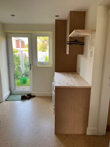 Bright interior with a wooden countertop, shelving, and a door leading to a garden.
