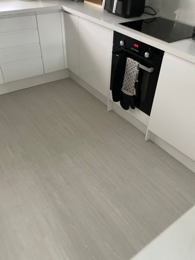 Modern kitchen with light flooring and an oven under a countertop.