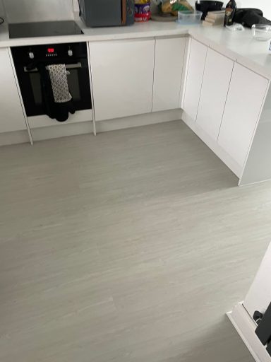 Modern kitchen with a grey floor and white cabinets, featuring an oven.