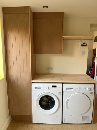 Laundry area featuring a washing machine and a dryer beneath wooden cabinetry.