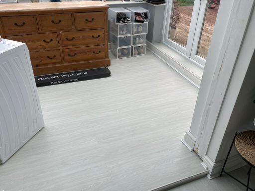 Light-coloured wooden flooring in a room with a wooden dresser and storage boxes.