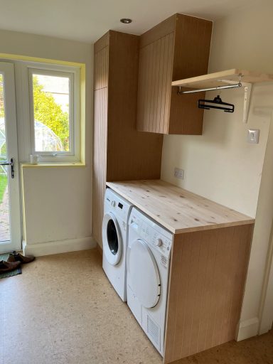 Laundry area featuring a washing machine and dryer with wooden cabinetry.