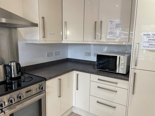 Modern kitchen with cream cabinets, grey countertops, microwave, kettle, and gas hob.