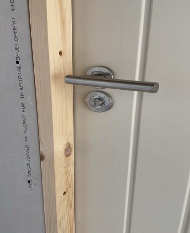 Close-up of a door handle and lock on a white door frame.