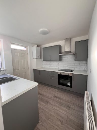 Modern kitchen featuring grey cabinets, white countertops, and tiled backsplash.