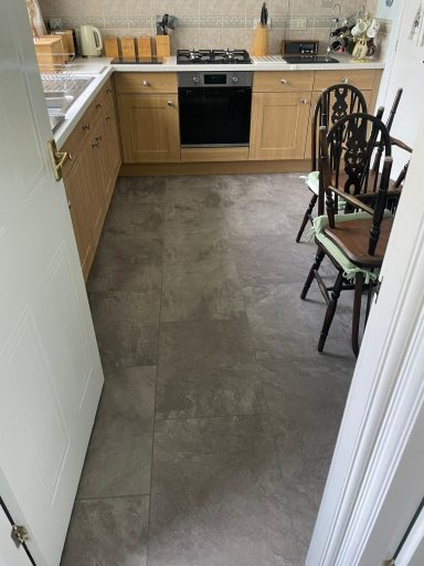 Kitchen interior with wooden cabinets, a stove, and a chair on the floor.