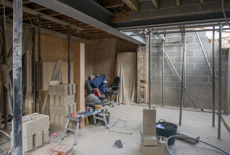 Construction site with workers, materials, and scaffolding in an unfinished interior.