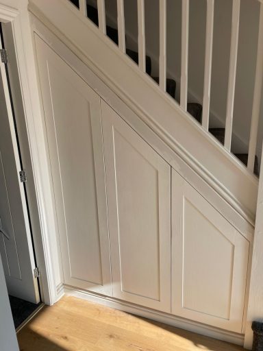 White wooden panels under a staircase with a wooden floor.