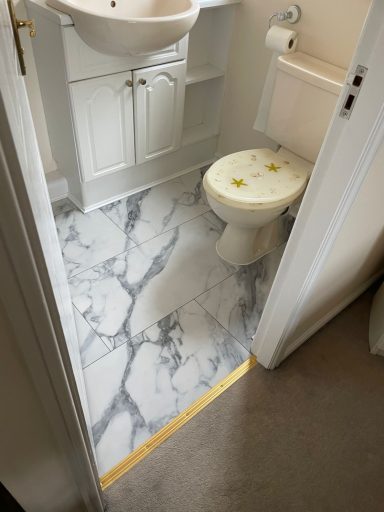Small bathroom featuring marble flooring, a toilet, and a sink with storage.